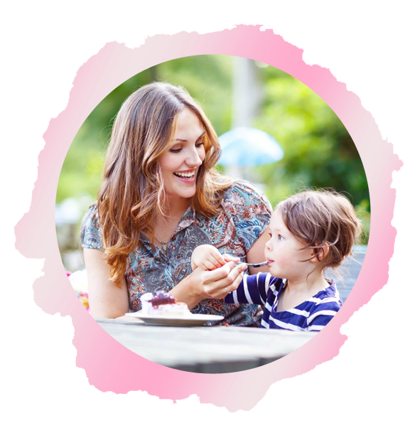 A woman and child eating at an outdoor table.